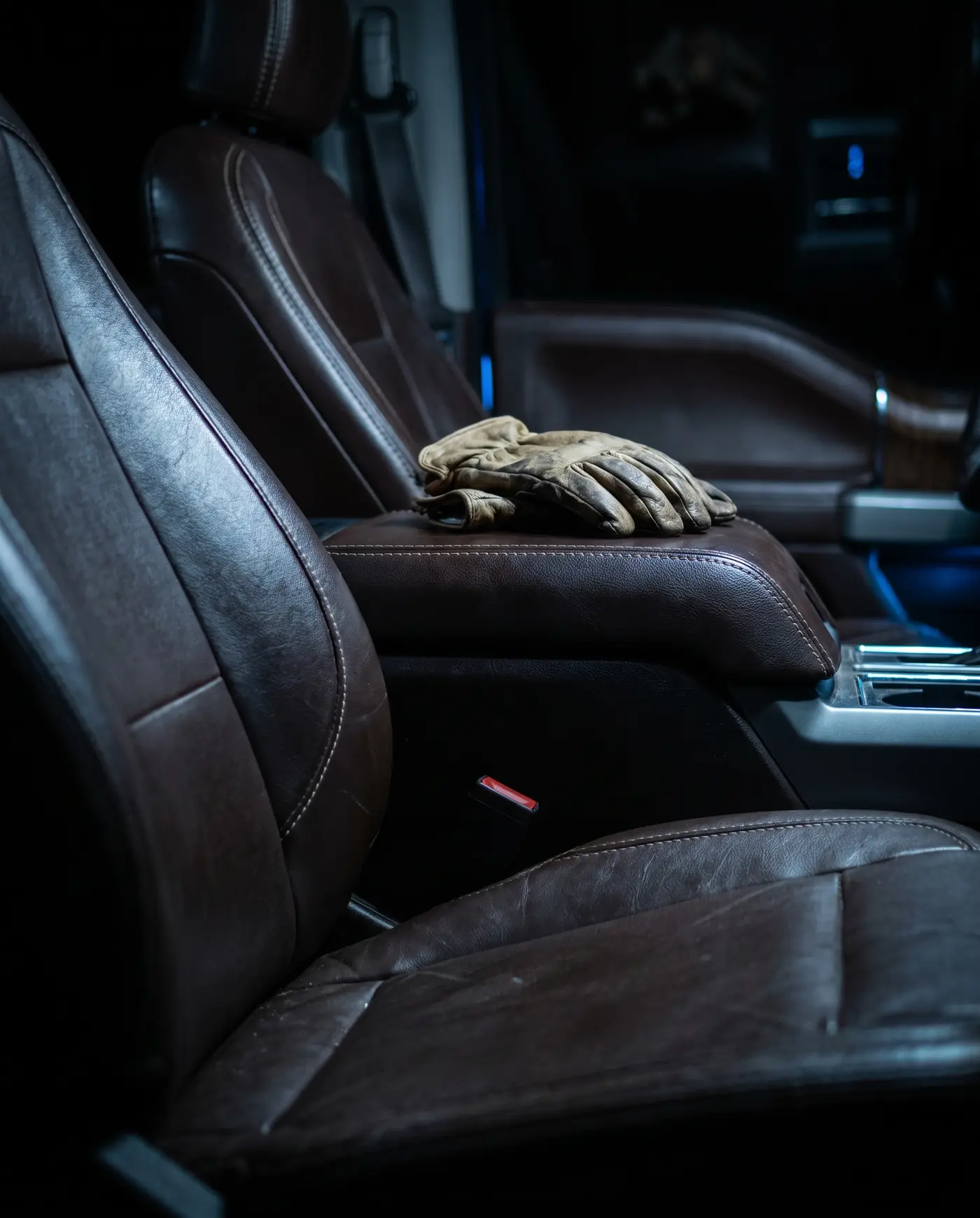 Worn leather work gloves resting on a truck's leather center console